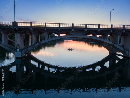 Kayakers on the Colorado River at sunset. A road bridge crosses the river. Austin, Texas, United States. photo