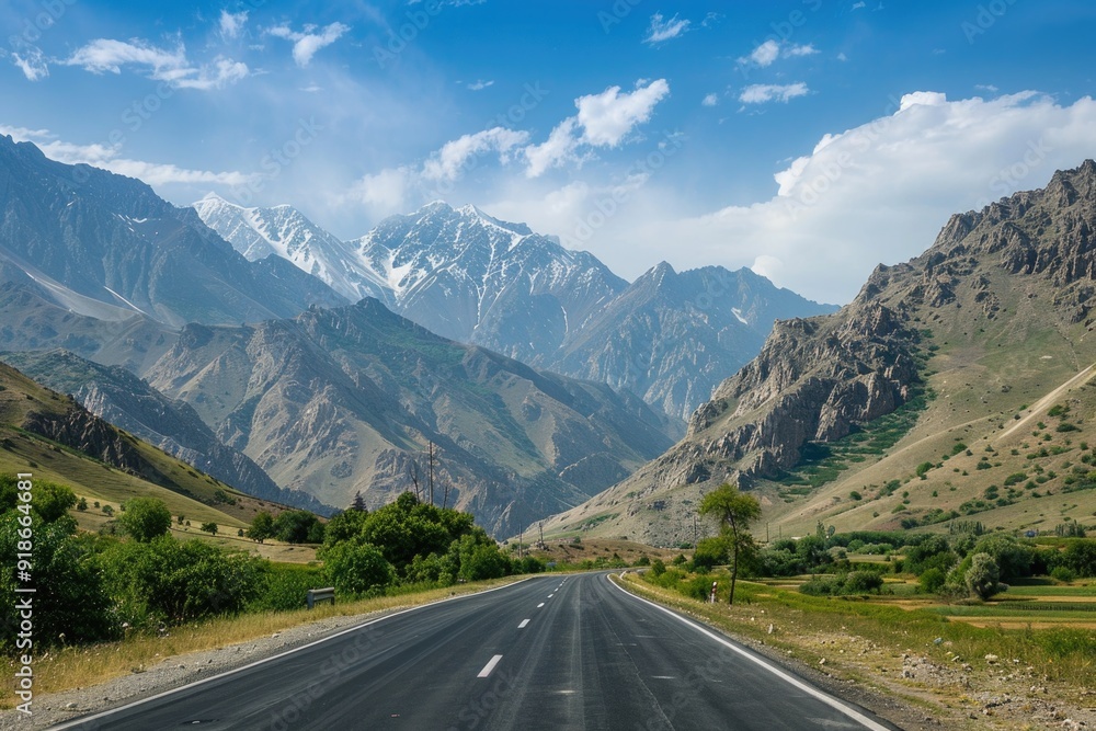 Fototapeta premium A scenic highway winding through mountains with lush greenery and blue skies