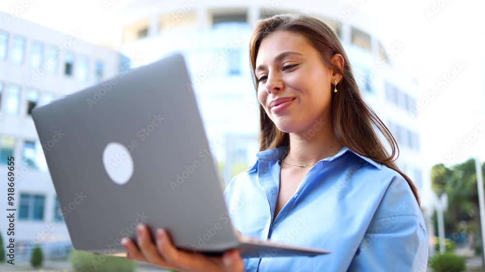 Beautiful, young businesswoman standing on the street and using laptop Beautiful, young businesswoman standing on the street and using laptop