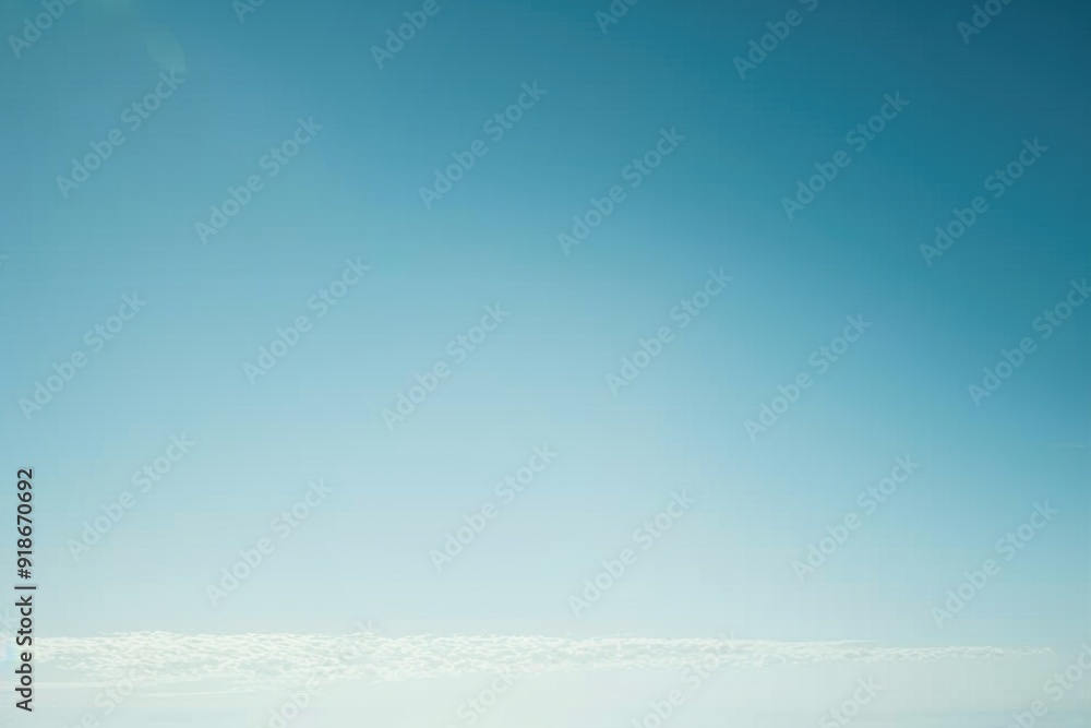 Fototapeta premium A person stands on a sunny beach flying a colorful kite high in the sky