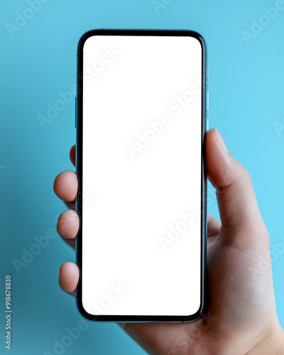A hand holding a smartphone with a blank screen against a blue background, ideal for copy space and custom content.
