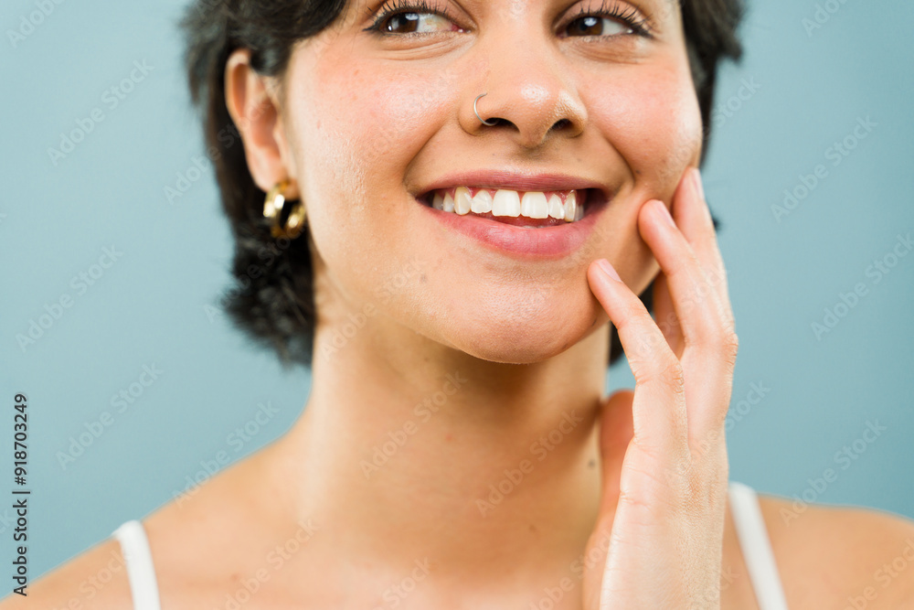 Close-up of a young woman with perfect smile gently touching her face with hand Close-up of a young woman with perfect smile gently touching her face with hand