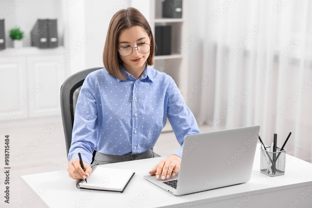 Teenager taking notes while working with laptop at home. Remote job Teenager taking notes while working with laptop at home. Remote job
