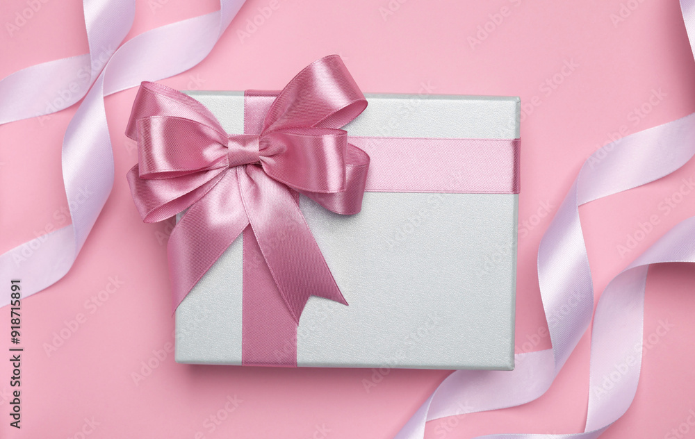 Beautiful gift box with color bow and ribbons on pink background, flat lay Beautiful gift box with color bow and ribbons on pink background, flat lay
