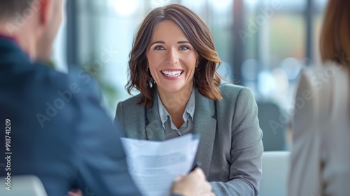 Fototapeta Naklejka Na Ścianę i Meble -  Smiling mature business woman hr holding cv document at job interview. Happy mid aged professional banking manager or lawyer consulting client sitting at workplace in corporate office meeting.