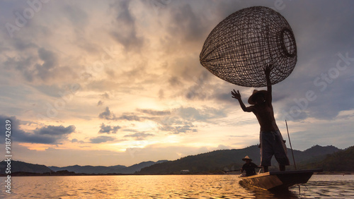 A fisherman casting his net into the river, surrounded by splashing water droplets under the golden sunset sky. photo