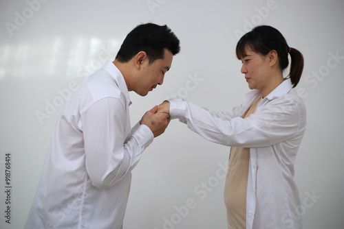 A young man hugs his pregnant wife while standing in a room in his house.