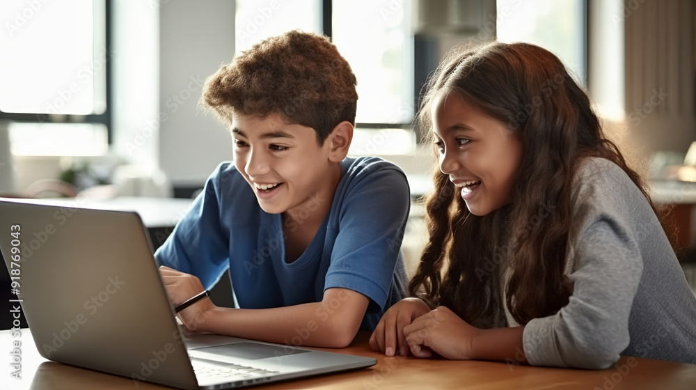 A photo of two middle school students sitting at a table looking into an open laptop, smiling and learning together. A photo of two middle school students sitting at a table looking into an open laptop, smiling and learning together.