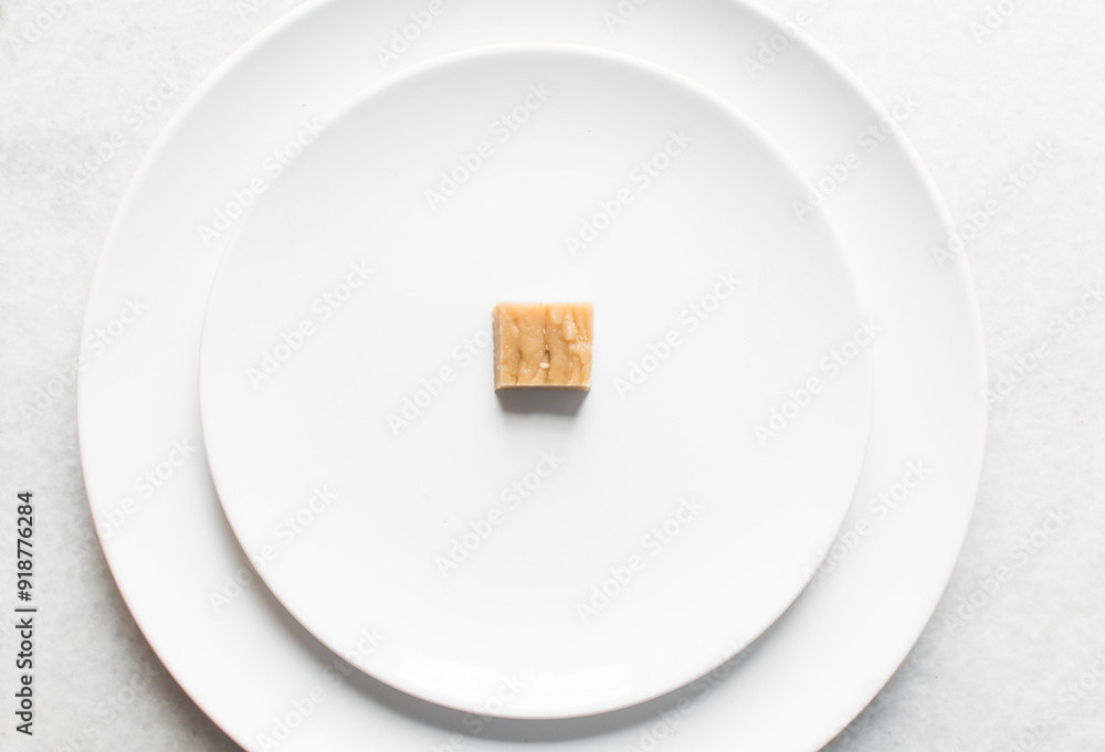 Overhead view of sliced peanut butter fudge on a white plate, top view of soft peanut fudge squares on a white ceramic plate Overhead view of sliced peanut butter fudge on a white plate, top view of soft peanut fudge squares on a white ceramic plate