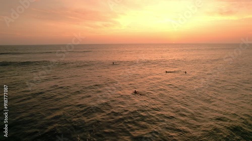 Video 4K con dron de surfistas en aguas pintadas por el sol color naranja