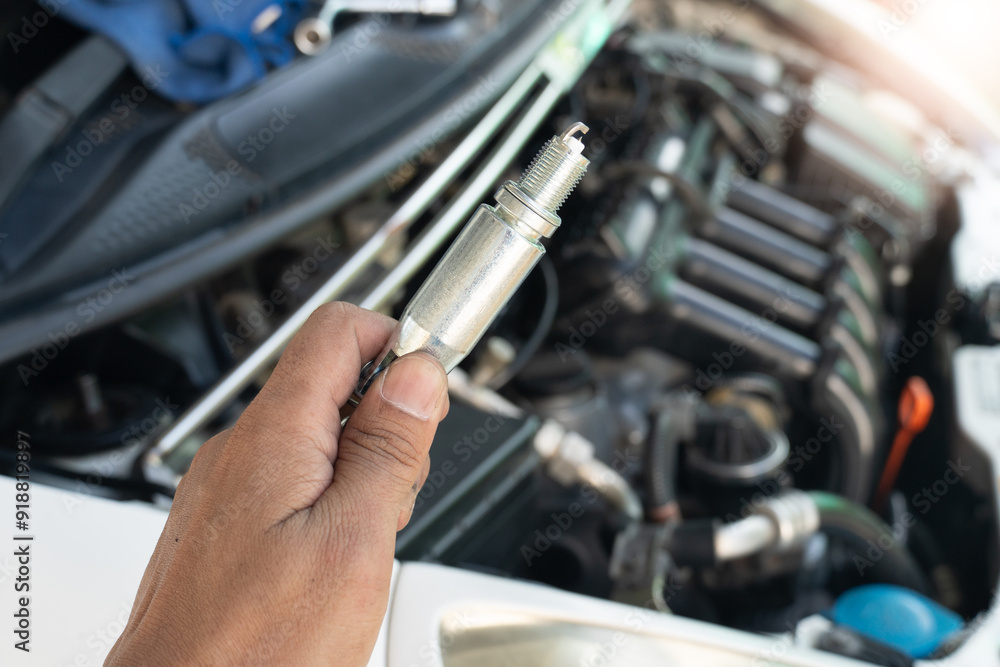 Car mechanic hand holding spark plug to repair car engine in garage. A set of socket wrenches to lock the spark plugs in place. ready to be put back into the engine system. Car mechanic hand holding spark plug to repair car engine in garage. A set of socket wrenches to lock the spark plugs in place. ready to be put back into the engine system.