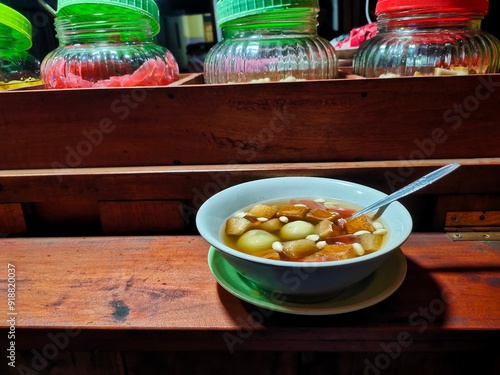 Wedang Ronde in a white bowl. Wedang Ronde, or Tangyuan, or glutinous sweet balls, is a Javanese traditional dessert made of glutinous rice flour filled with peanuts in ginger syrup. photo