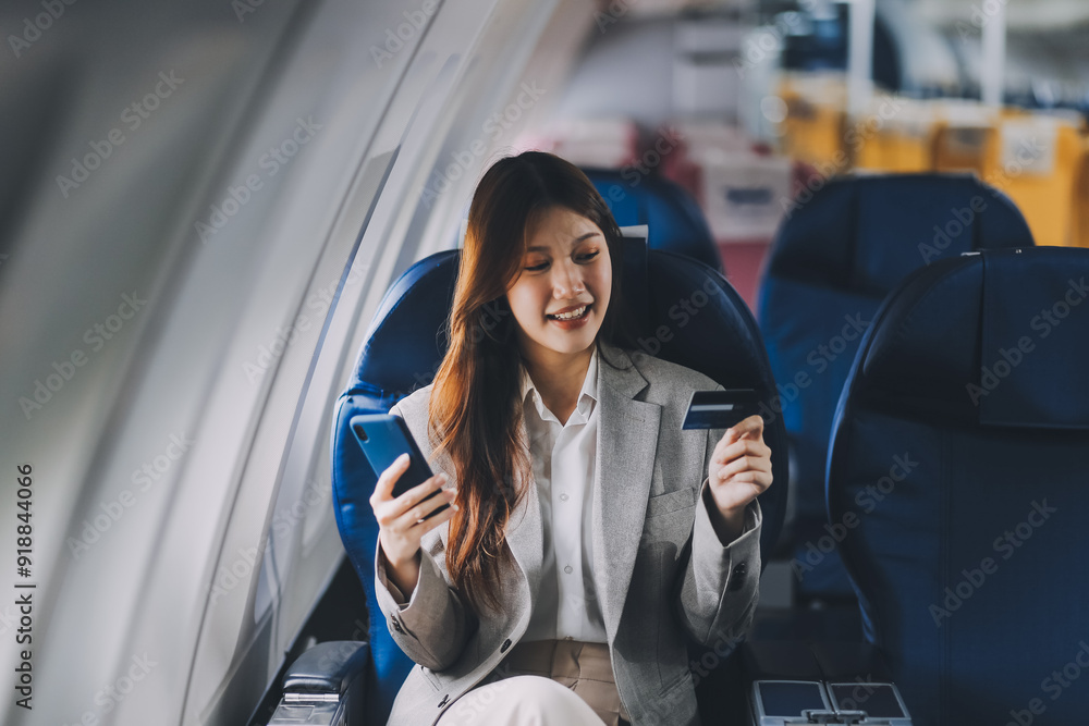Young businesswoman holding credit card near blurred devices in private plane Young businesswoman holding credit card near blurred devices in private plane