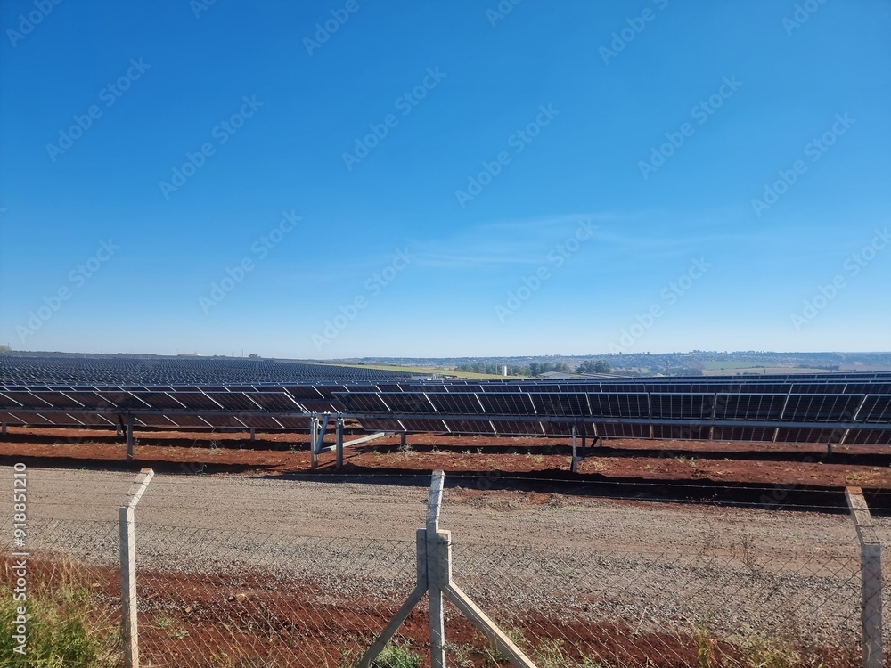 Fototapeta premium Solar panels in a vast array at a renewable energy farm under clear blue skies during the day