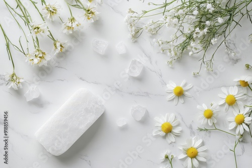 Crystal alum deodorant and chamomile flowers on white marble photo