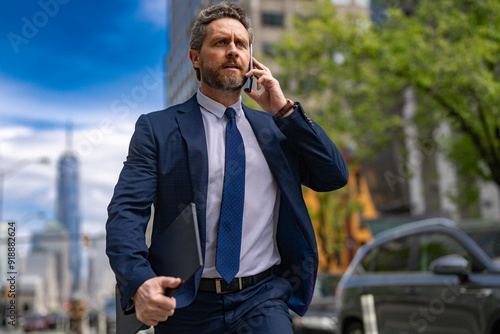 Businessman with phone run in NY. Business talk. Businessman run down street talking on the phone. Man in suit late. Business call. Running business man. Fast business. Run and late businessman. photo