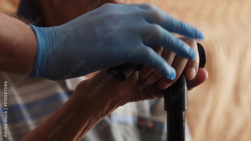 doctor helps pensioner to stand up sitting with walking stick to get up and walk, caregiver in nursing home wearing gloves taking care of pensioner doctor helps pensioner to stand up sitting with walking stick to get up and walk, caregiver in nursing home wearing gloves taking care of pensioner