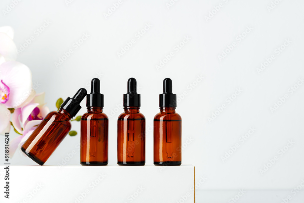 Four Amber Glass Dropper Bottles With White Background and Orchid Bloom Four Amber Glass Dropper Bottles With White Background and Orchid Bloom