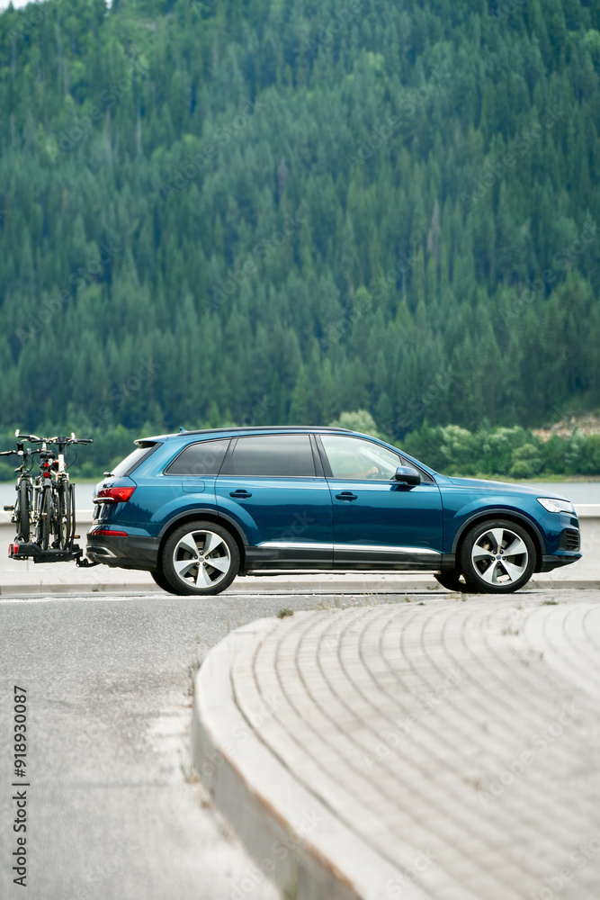 Side view of SUV with bikes driving near Alps Side view of SUV with bikes driving near Alps