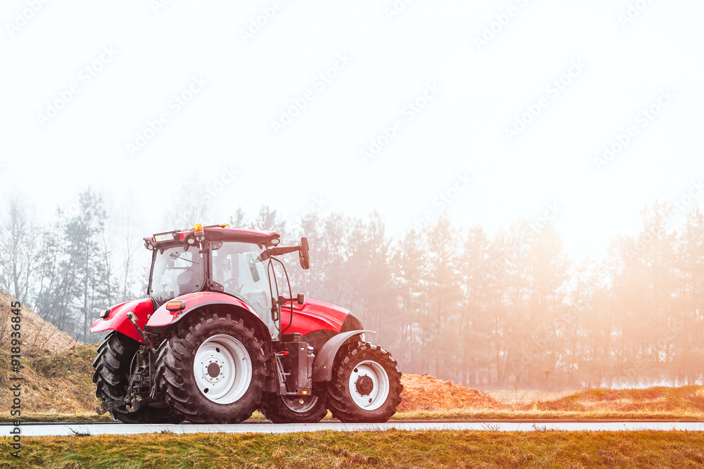 Obraz premium Modern tractor working in agricultural field on misty day