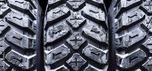 Close up of three new black off road tires. The tires have a deep tread pattern, and are ready for action. photo