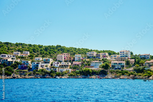 Seaside town with colorful coastal houses on hillside with boats docked along clear blue waters. Residential apartments for summer vacation on Adriatic Sea in Rogoznica, Croatia