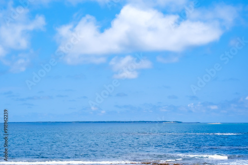 沖縄の青い海に浮かぶ平らな島影
