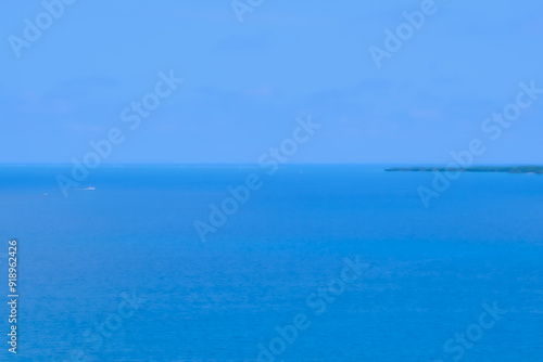 沖縄の青い海と海岸に打ち寄せる白い波、疾走するボート
