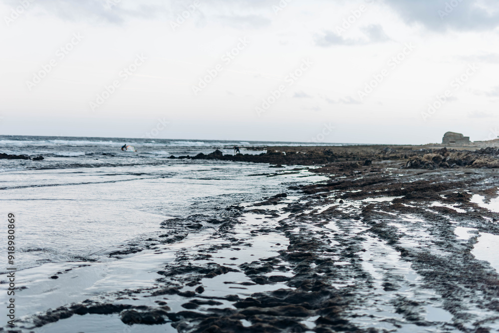 Man professional surfer standing on the sandy beach with his kite and board. Windsurfing, Extreme Sport Man professional surfer standing on the sandy beach with his kite and board. Windsurfing, Extreme Sport