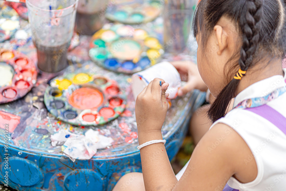Closeup and back view of Asian primary students girl holding paint brush study and learning paint on plaster doll in the art classroom. Closeup and back view of Asian primary students girl holding paint brush study and learning paint on plaster doll in the art classroom.