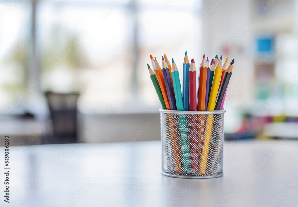 Colorful pencils standing in a pencil holder on a white table with blurred background