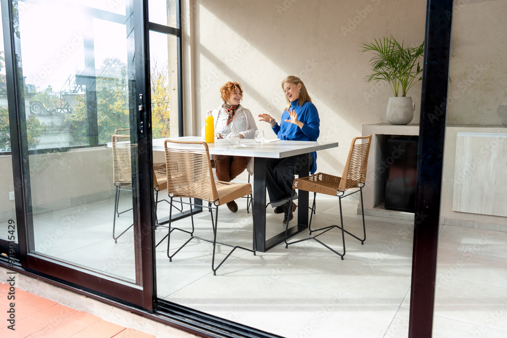 Mid-adult female friends enjoying a morning chat Mid-adult female friends enjoying a morning chat