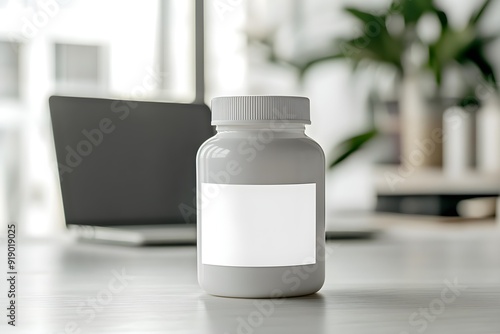 White pill bottle with a blank label on a desk with a laptop in the background. Concept of pharmaceutical or supplement product mockup in a modern workspace