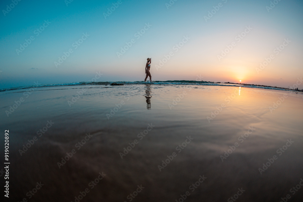 silhouette of a woman walking along the beach. Meditation of the spiritual world. Happy girl walks along the beach against the backdrop of sunset. silhouette of a woman walking along the beach. Meditation of the spiritual world. Happy girl walks along the beach against the backdrop of sunset.