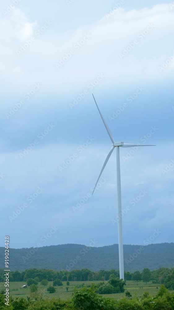wind turbines stand tall in the landscape of rural area on the mountain for generating electricity, sustainable energy solutions and green energy concept. vertical footage wind turbines stand tall in the landscape of rural area on the mountain for generating electricity, sustainable energy solutions and green energy concept. vertical footage