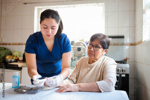 Nurse assists elderly woman with blood glucose test at home photo