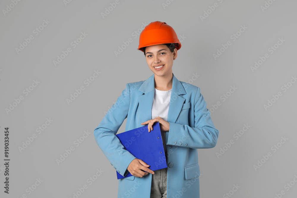 Engineer in hard hat with clipboard on grey background Engineer in hard hat with clipboard on grey background
