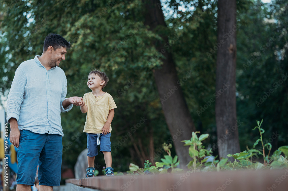 Father and son holding hands walking in garden Father and son holding hands walking in garden