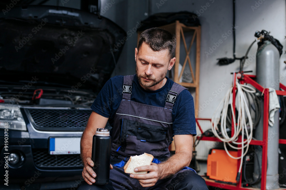 Auto repair specialist eating lunch in garage Auto repair specialist eating lunch in garage