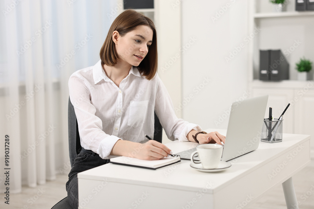 Teenager taking notes while working with laptop at home. Remote job Teenager taking notes while working with laptop at home. Remote job