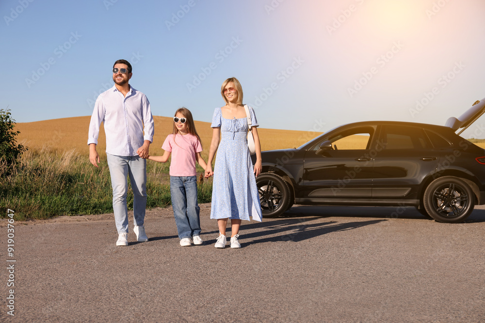 Happy family enjoying road trip. Parents and daughter near car Happy family enjoying road trip. Parents and daughter near car