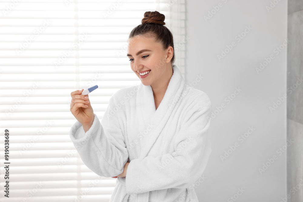 Happy woman holding pregnancy test in bathroom Happy woman holding pregnancy test in bathroom