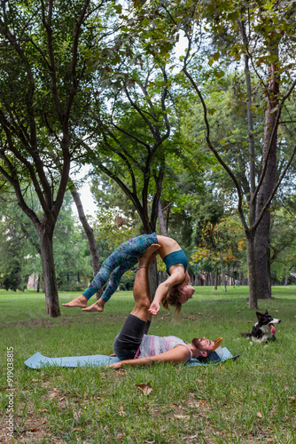 Focused couple practicing acroyoga in park in summer time