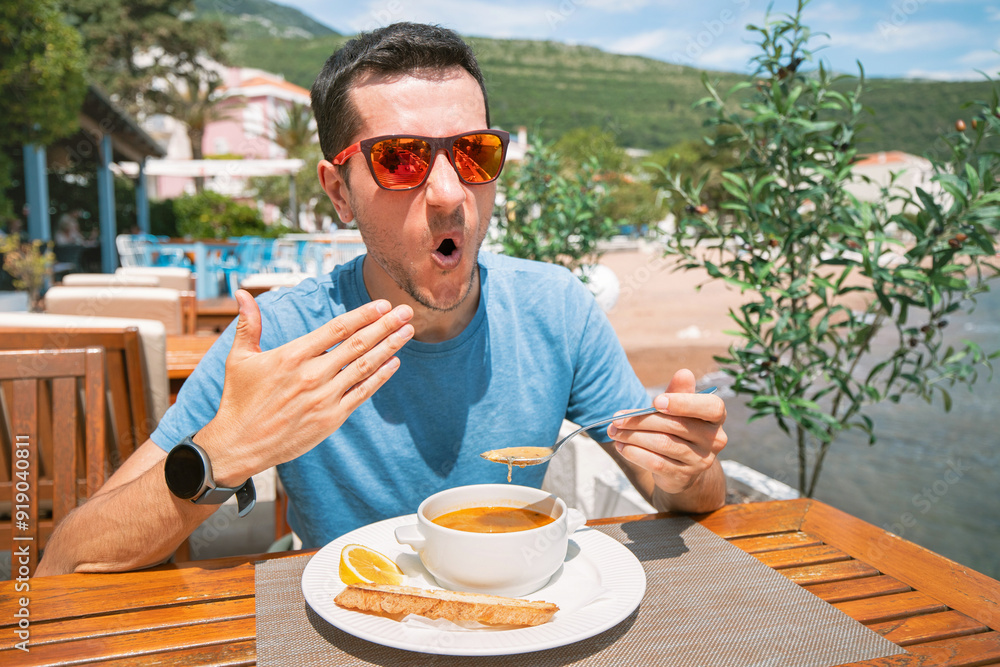 A man holding a bowl of hot and spicy soup, enjoying a satisfying lunch.