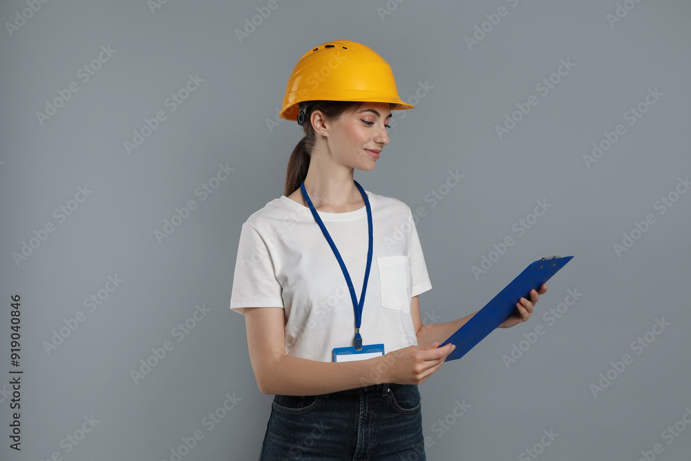 Engineer in hard hat with clipboard on grey background Engineer in hard hat with clipboard on grey background
