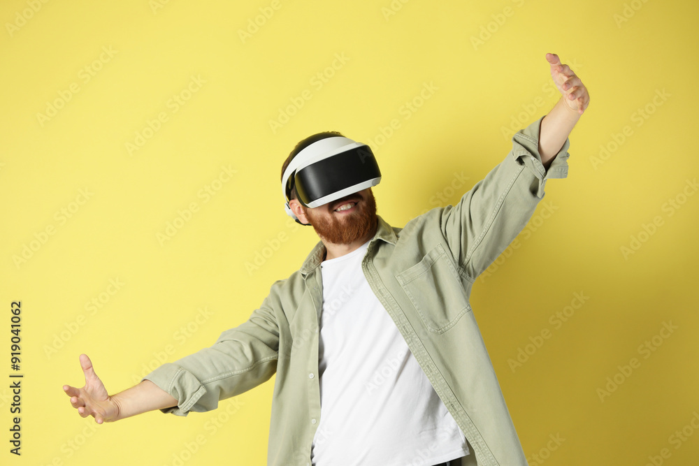 Happy man using virtual reality headset on pale yellow background Happy man using virtual reality headset on pale yellow background