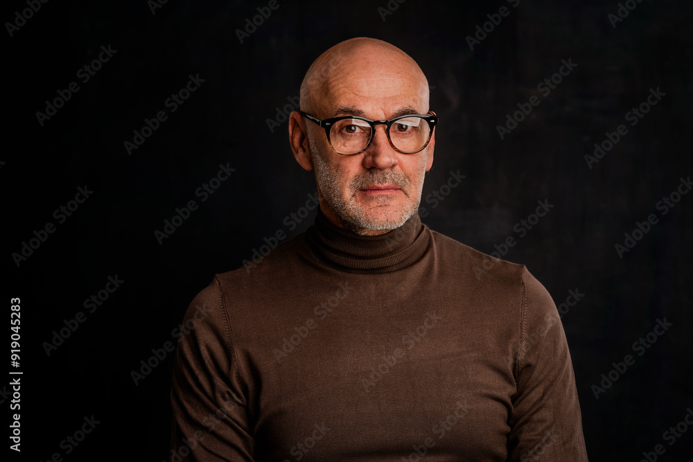 Studio portrait of an elderly man sitting against isolated dark background Studio portrait of an elderly man sitting against isolated dark background
