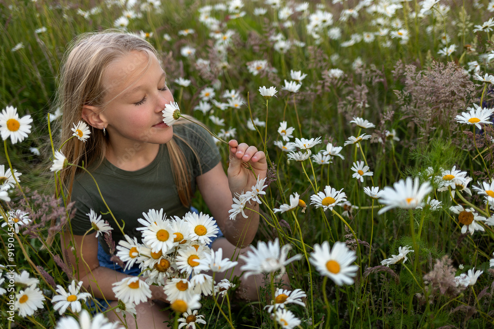 Girl smelling flower and sitting in daisy field Girl smelling flower and sitting in daisy field