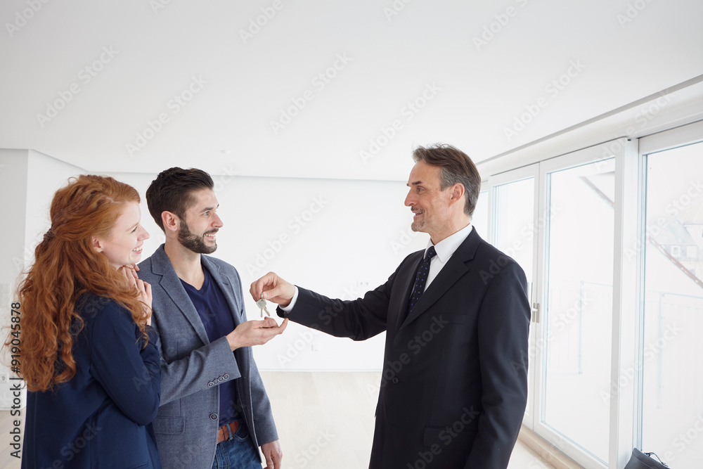 Real estate agent giving keys to happy couple at new house Real estate agent giving keys to happy couple at new house