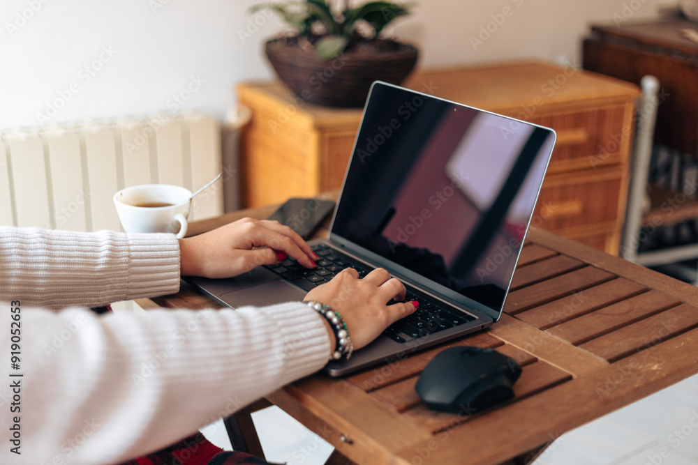Faceless woman typing on laptop in modern home Faceless woman typing on laptop in modern home